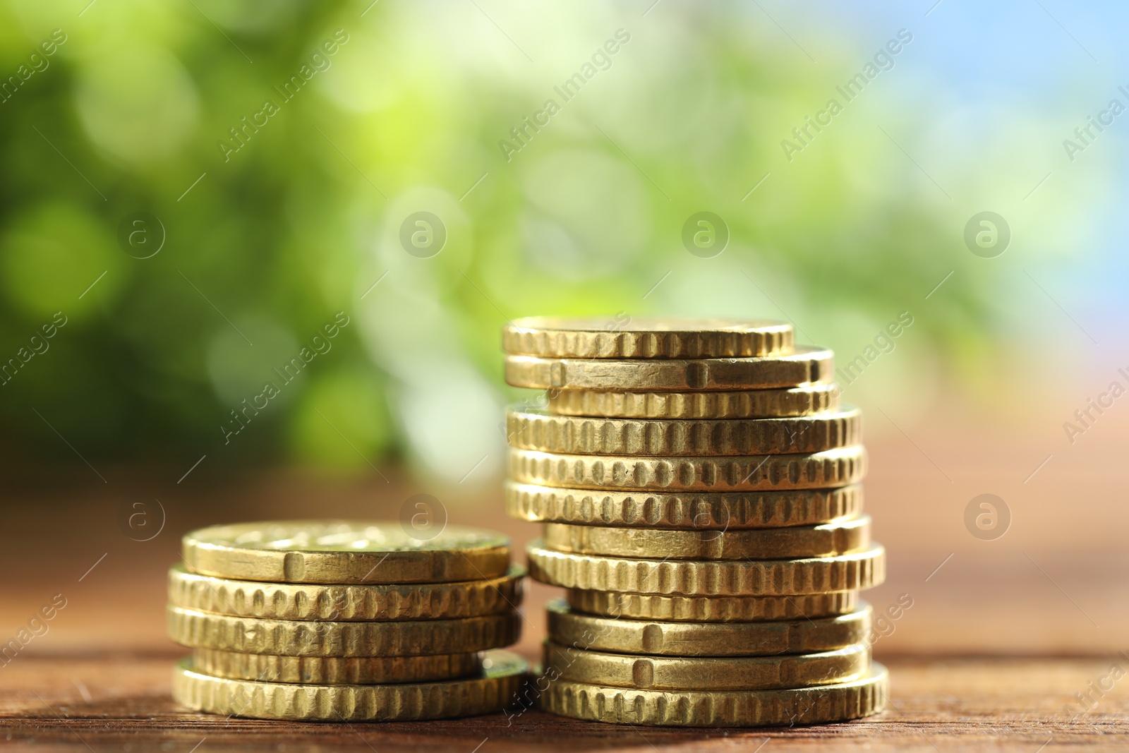 Photo of Stacks of euro coins on wooden table, closeup