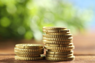 Photo of Stacks of euro coins on wooden table, closeup