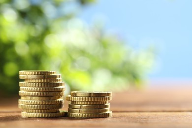 Photo of Stacked euro coins on wooden table, space for text