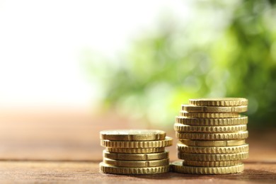 Photo of Stacked euro coins on wooden table, space for text