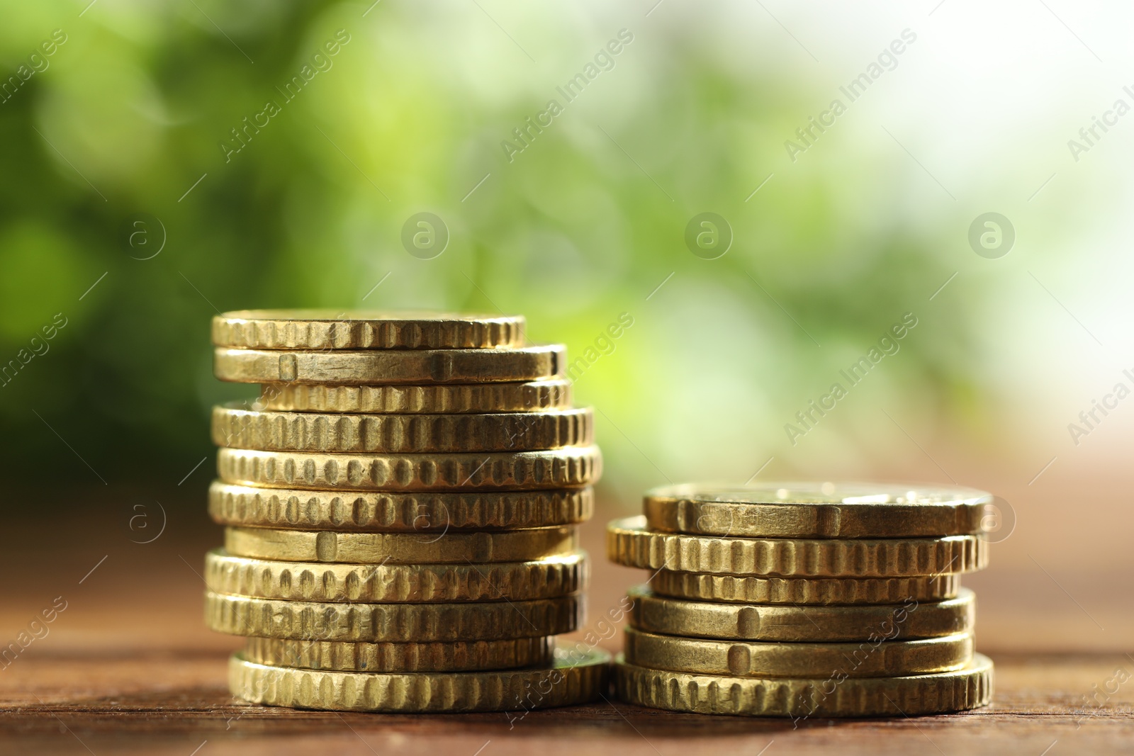 Photo of Stacks of euro coins on wooden table, closeup