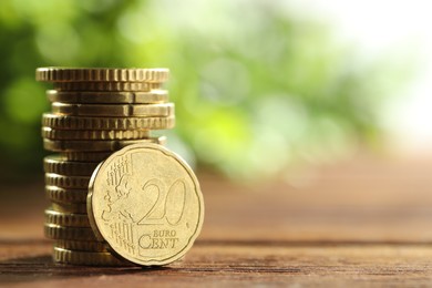 Photo of Stacked euro coins on wooden table, space for text