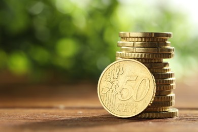 Photo of Stacked euro coins on wooden table, space for text