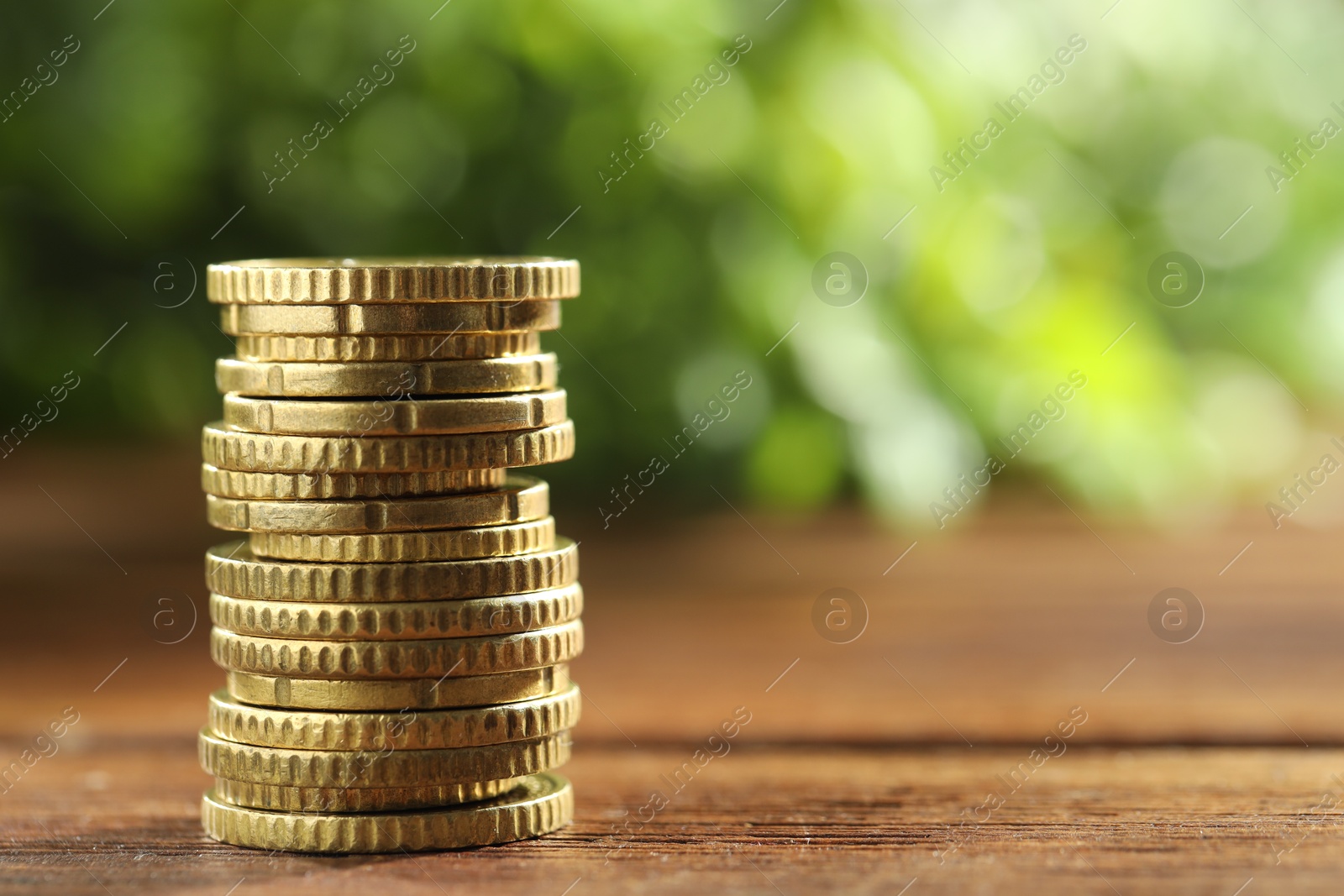 Photo of Stacked euro coins on wooden table, space for text