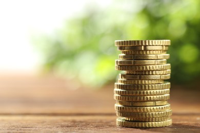 Photo of Stacked euro coins on wooden table, space for text