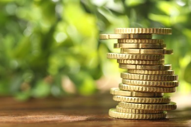 Photo of Stacked euro coins on wooden table, space for text