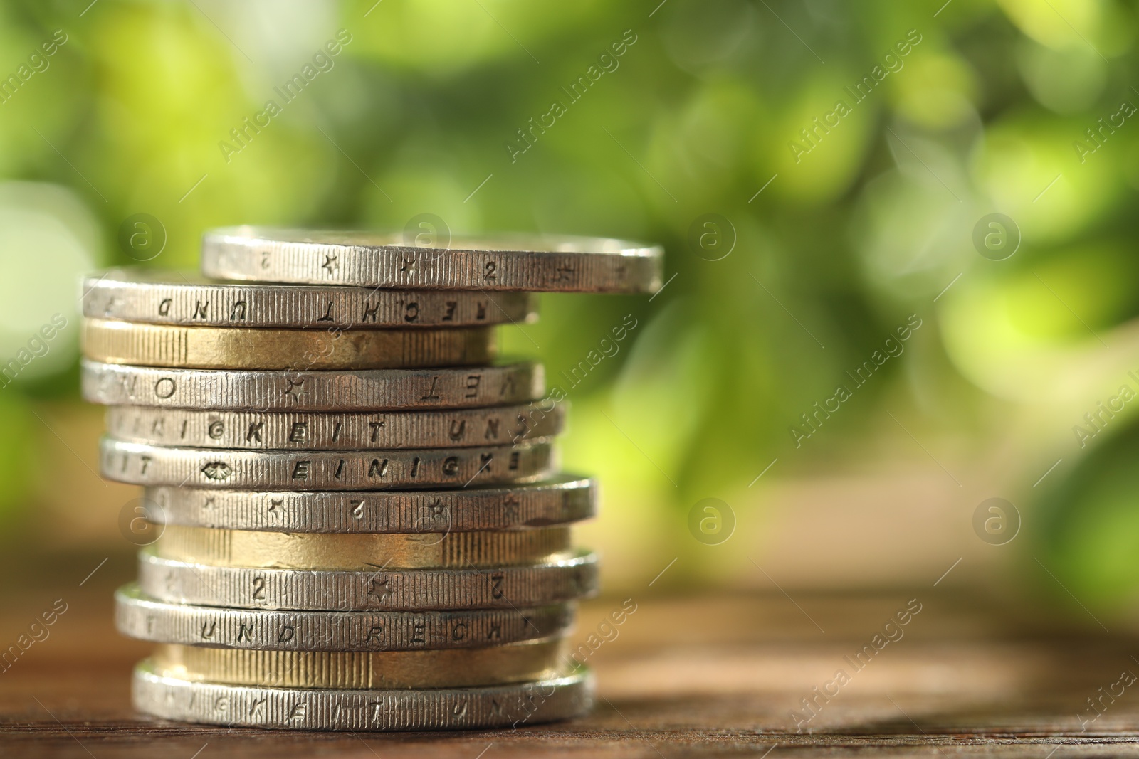 Photo of Stack of euro coins on wooden table, closeup. Space for text