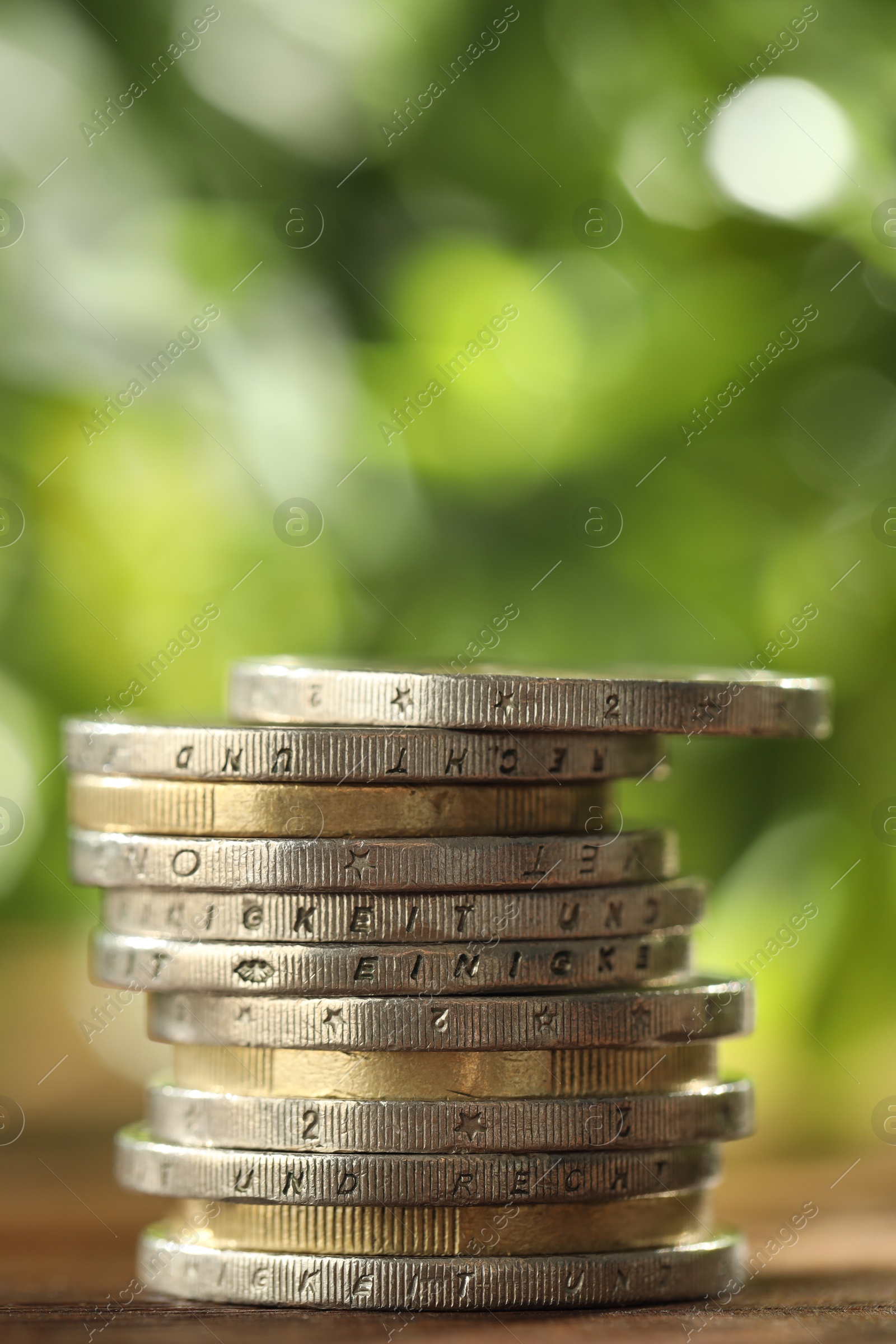 Photo of Stack of euro coins on wooden table, closeup