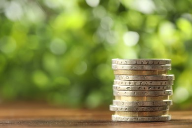 Photo of Stacked euro coins on wooden table, space for text