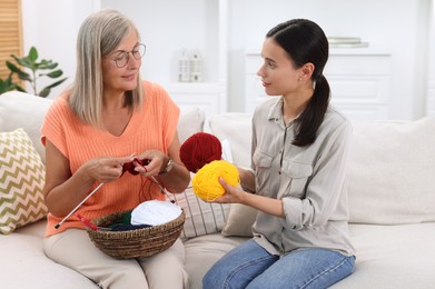 Photo of Mother and daughter with skeins of yarn spending time together at home