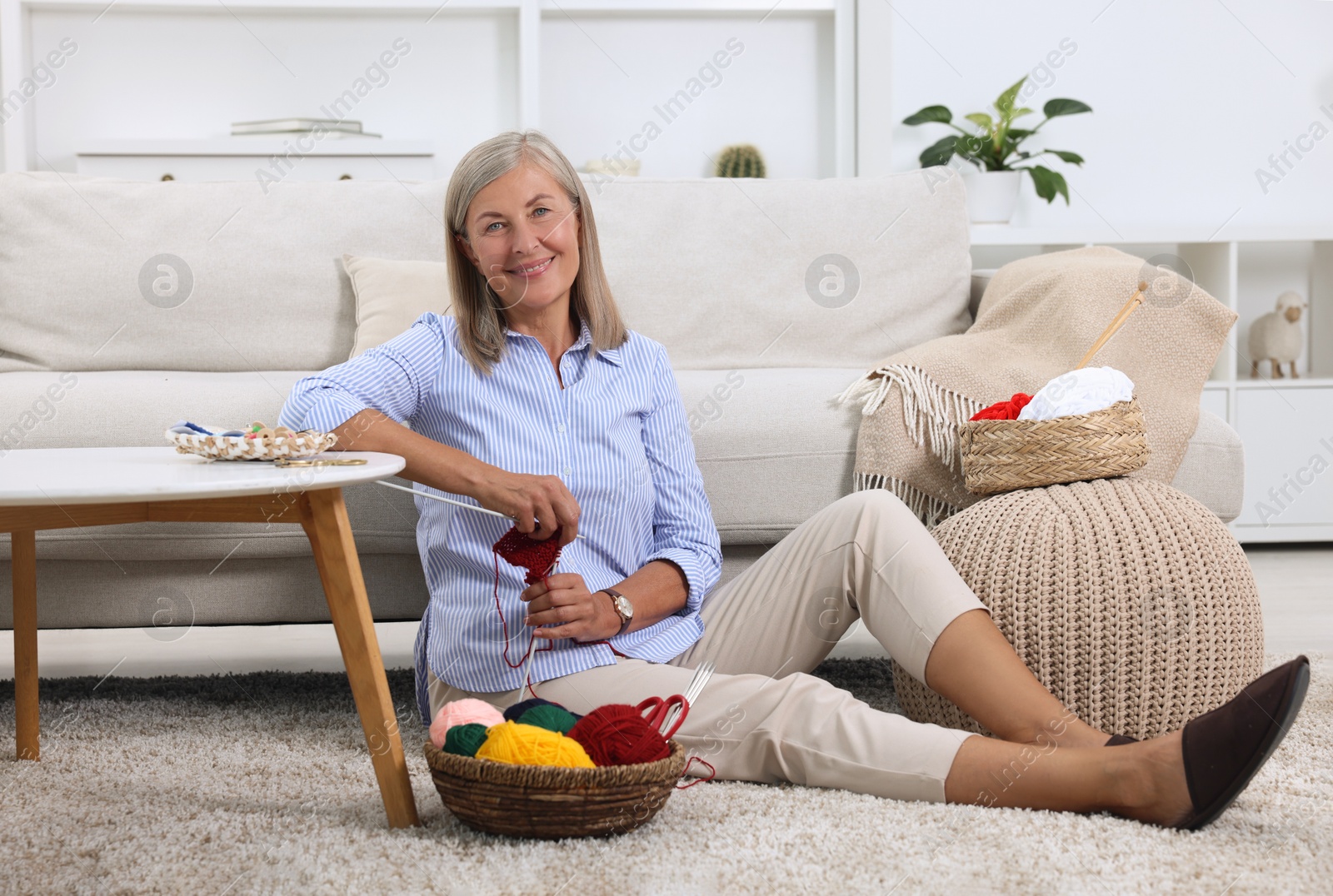 Photo of Smiling woman with skeins of yarn near sofa at home