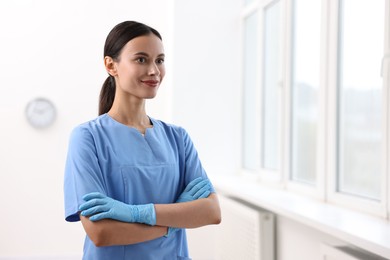 Photo of Beautiful nurse with crossed arms in clinic. Space for text