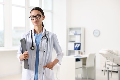 Smiling nurse with clipboard in clinic. Space for text