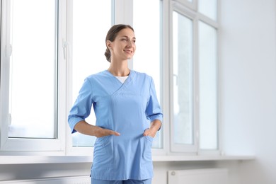 Photo of Nurse in medical uniform near window indoors