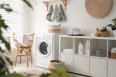 Photo of Washing machine, towels and detergents in laundry room