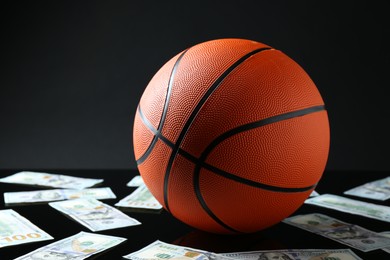 Photo of Basketball ball and dollar banknotes on black background