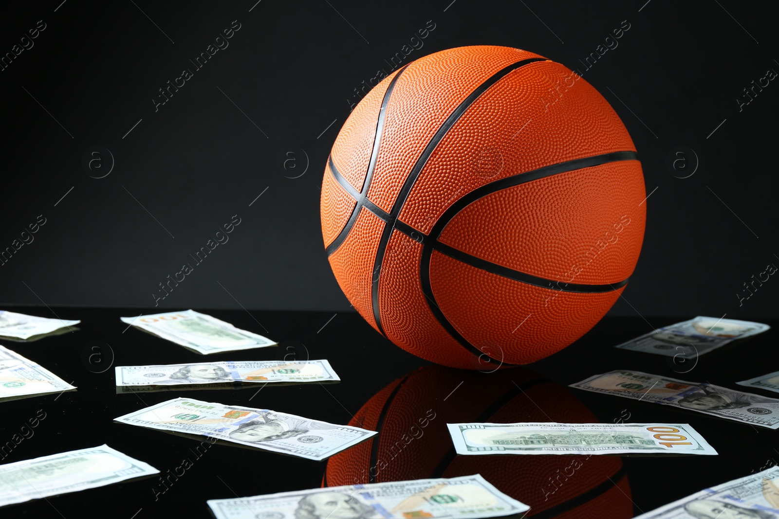 Photo of Basketball ball and dollar banknotes on black background