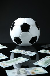 Photo of Soccer ball and dollar banknotes on black background