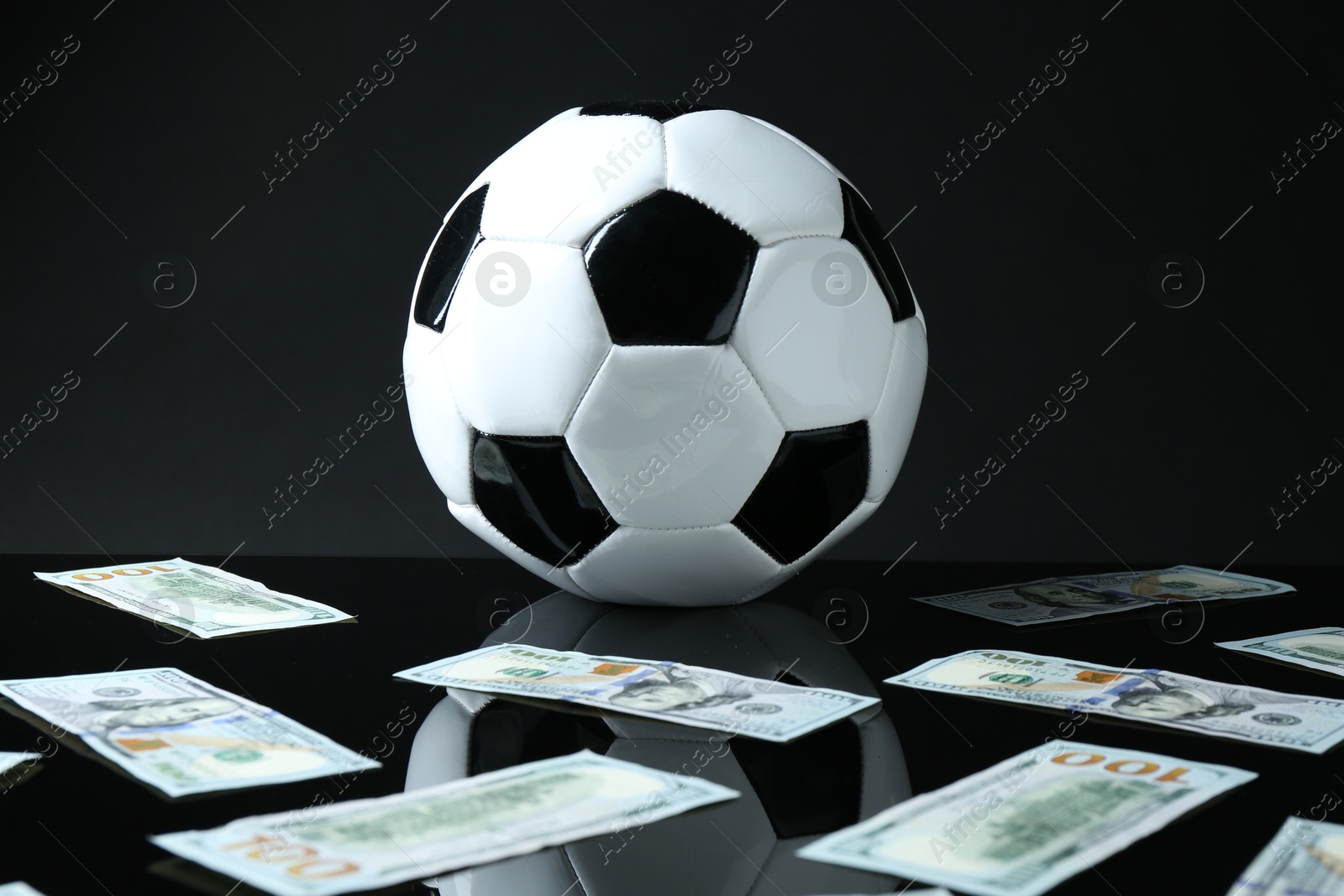 Photo of Soccer ball and dollar banknotes on black background