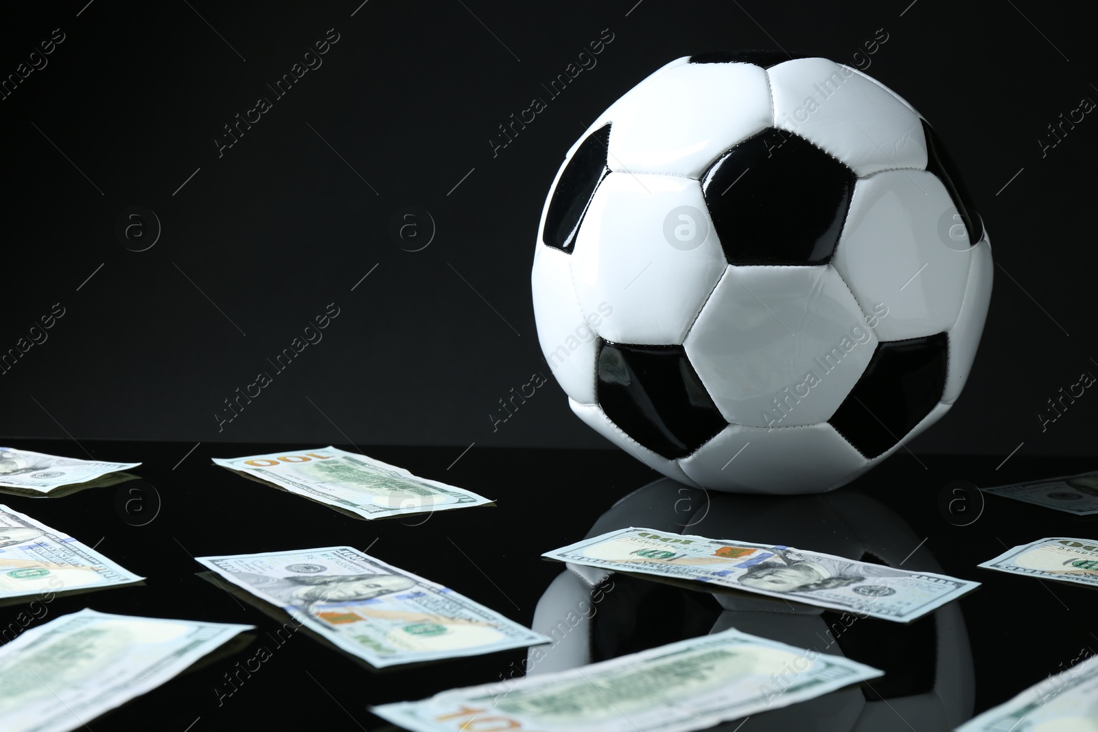 Photo of Soccer ball and dollar banknotes on black background