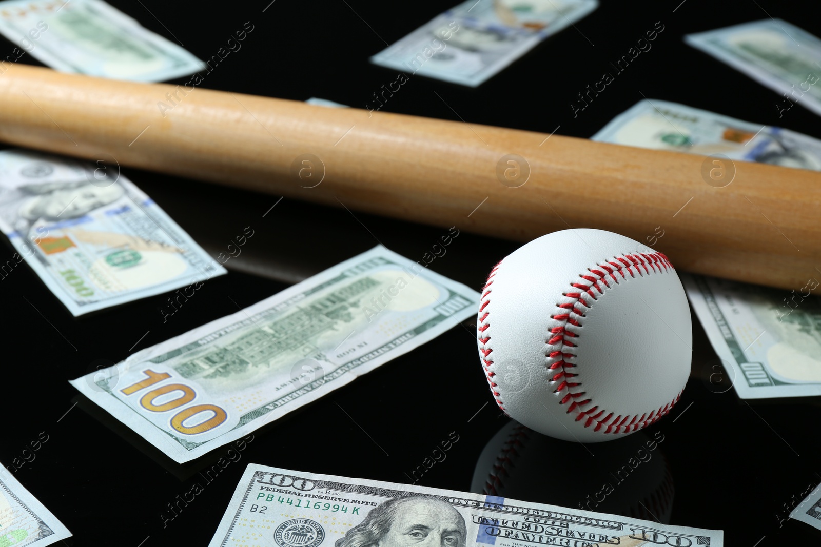 Photo of Baseball ball, bat and dollar banknotes on black background