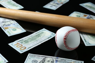 Photo of Baseball ball, bat and dollar banknotes on black background