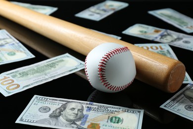 Photo of Baseball ball, bat and dollar banknotes on black background