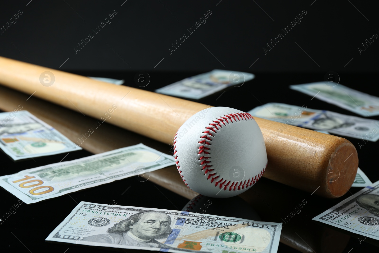 Photo of Baseball ball, bat and dollar banknotes on black background