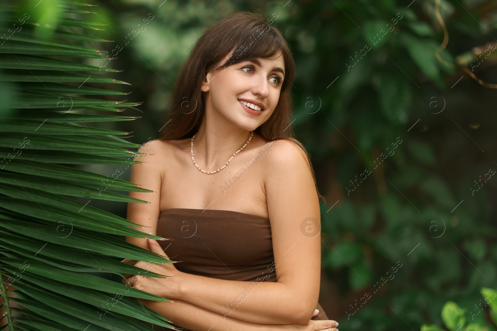 Photo of Portrait of smiling woman near palm leaves outdoors