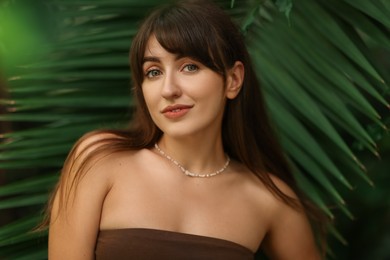 Portrait of beautiful woman near palm leaves outdoors