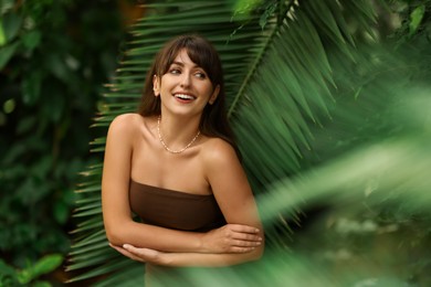 Portrait of smiling woman near palm leaves outdoors