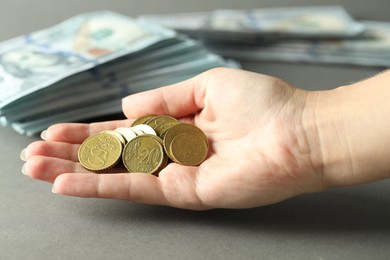 Photo of Woman with euro coins at grey table, closeup