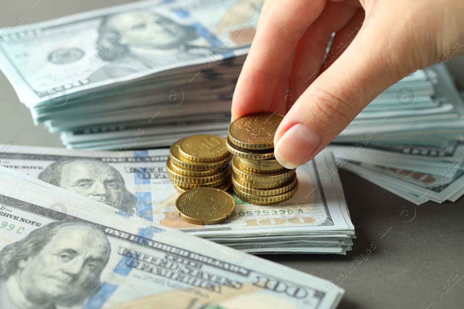 Photo of Woman stacking coins at grey table, closeup