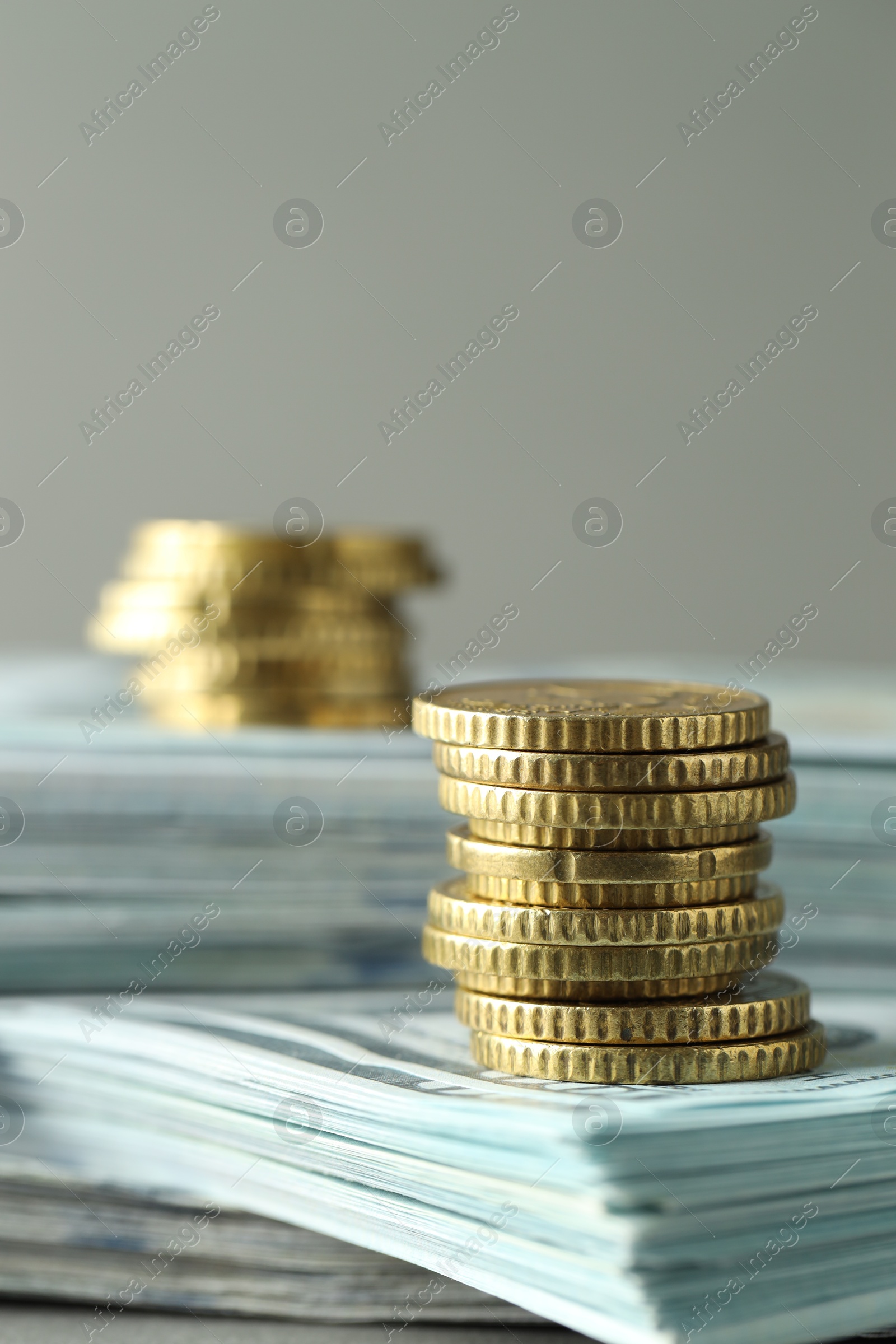 Photo of Stacked of euro coins and dollar banknotes on grey background, closeup