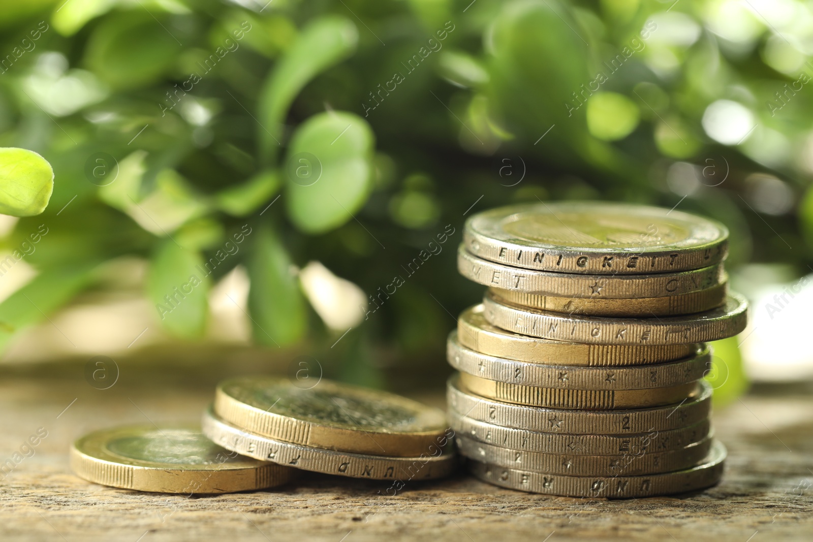 Photo of Stacked euro coins on wooden table outdoors, closeup