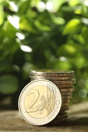 Photo of Stacked euro coins on wooden table outdoors, closeup