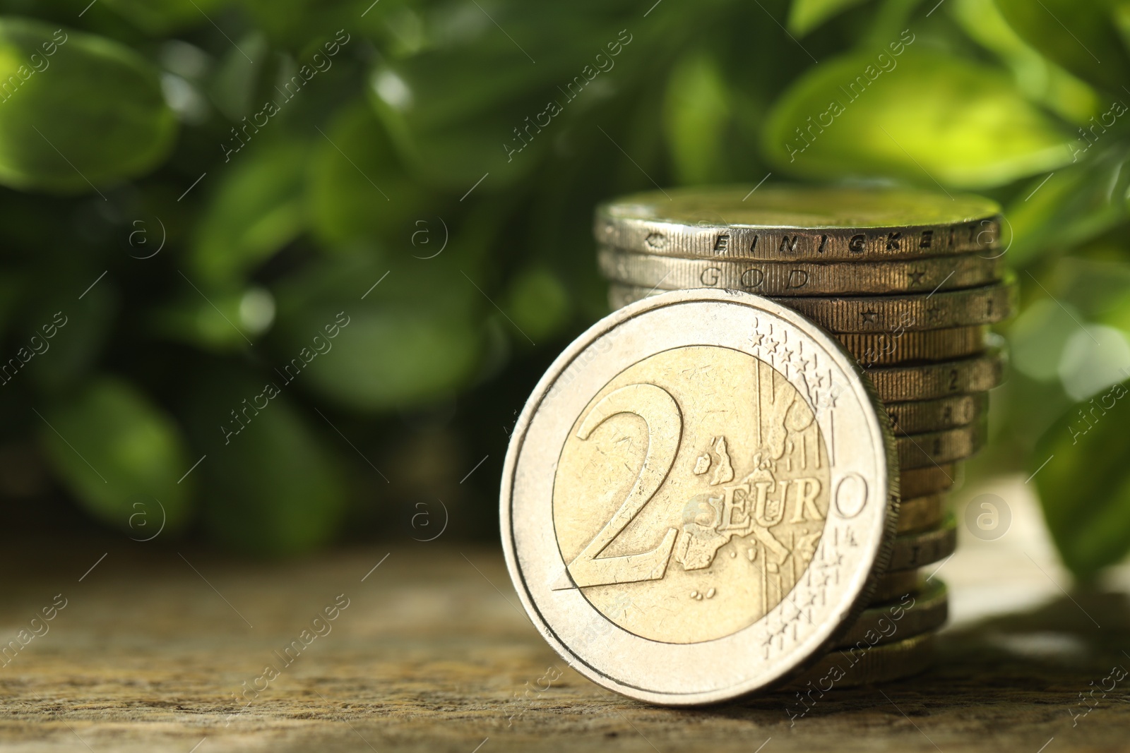 Photo of Stacked euro coins on wooden table outdoors, closeup. Space for text