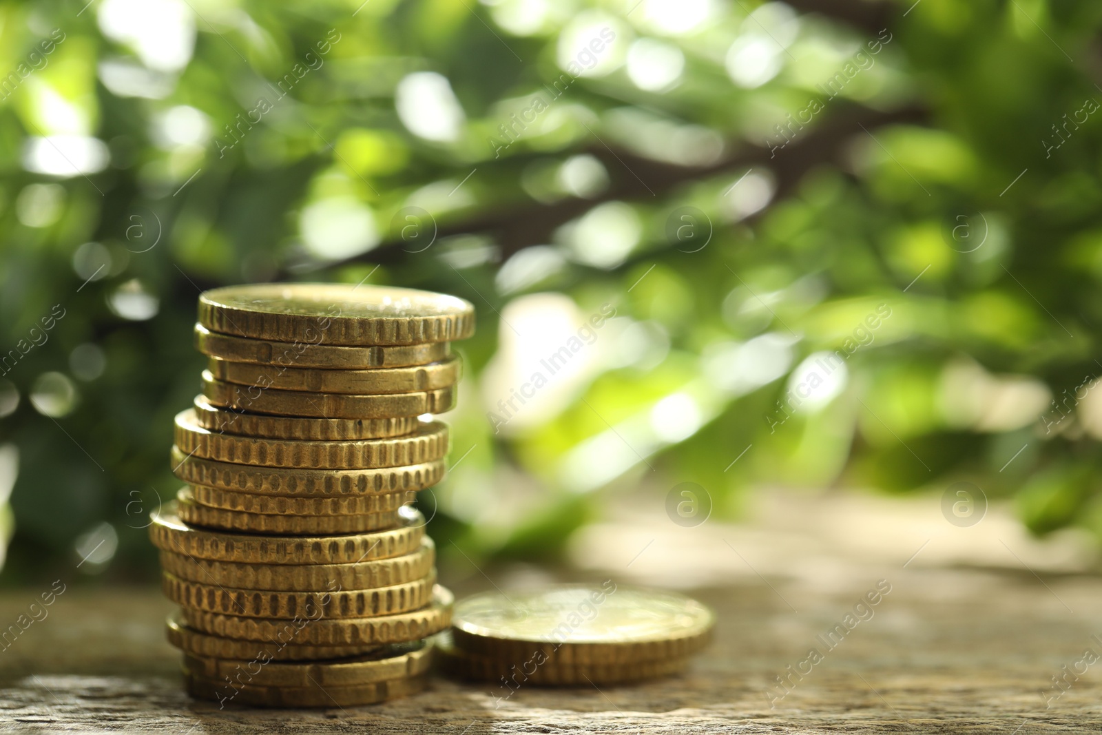 Photo of Stacked euro coins on wooden table outdoors, space for text