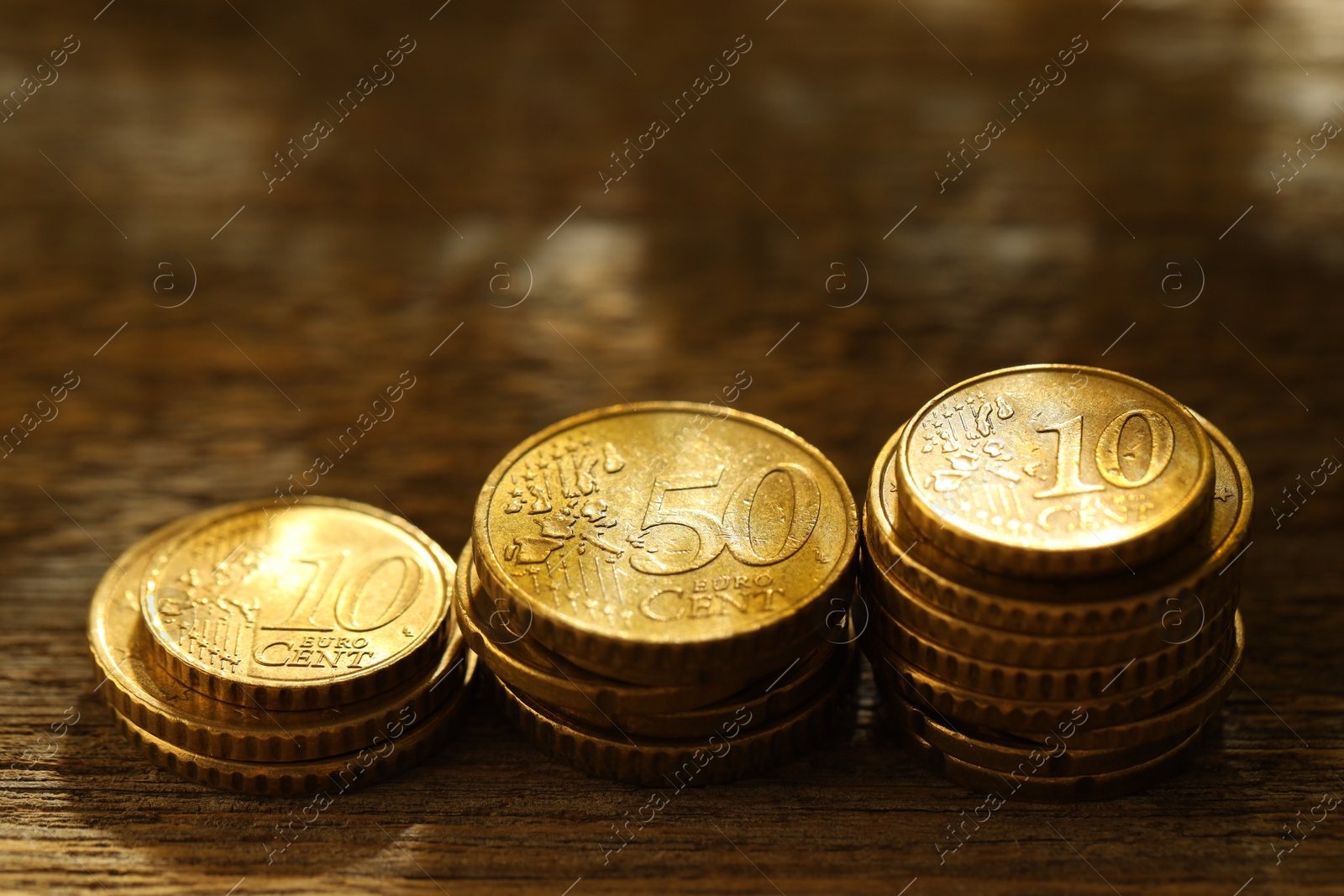 Photo of Stacked euro coins on wooden table, closeup