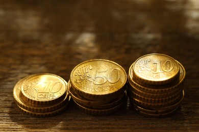 Photo of Stacked euro coins on wooden table, closeup