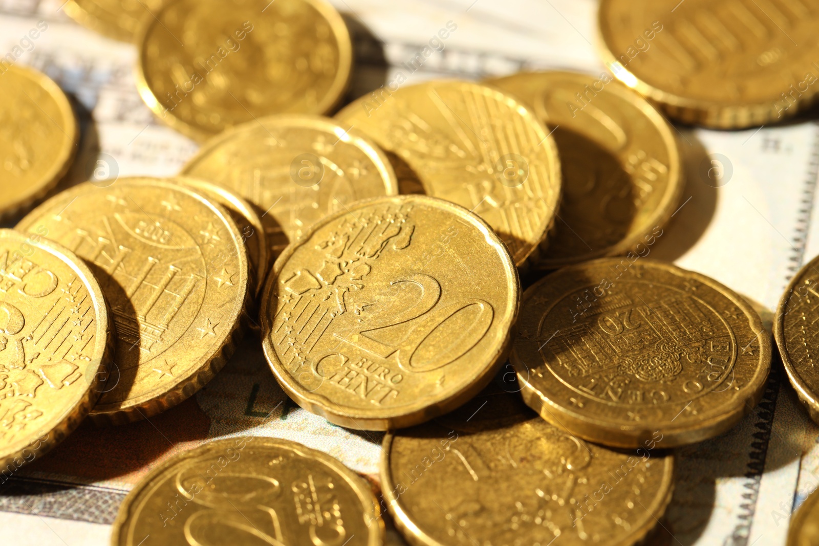 Photo of Many euro coins on dollar banknotes, closeup