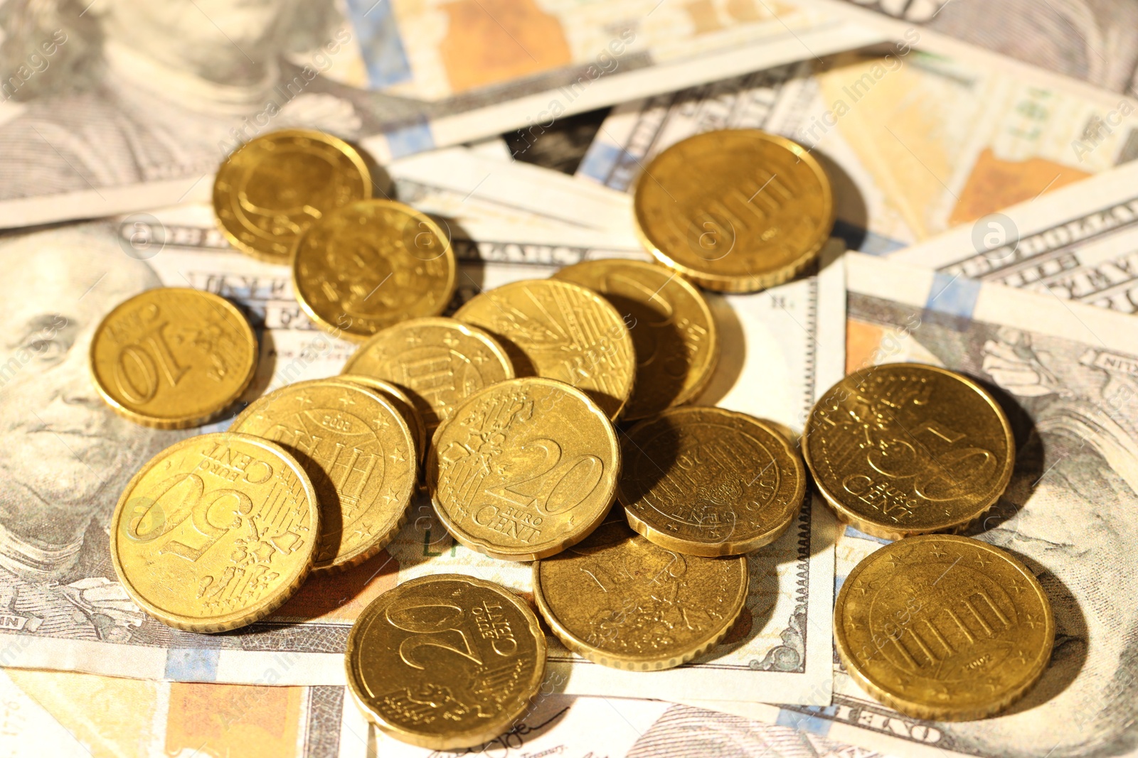 Photo of Many euro coins on dollar banknotes, closeup