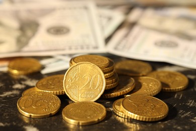 Photo of Many euro coins and dollar banknotes on dark table, closeup