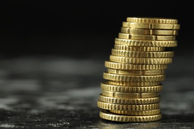 Photo of Stacked euro coins on dark table, closeup. Space for text