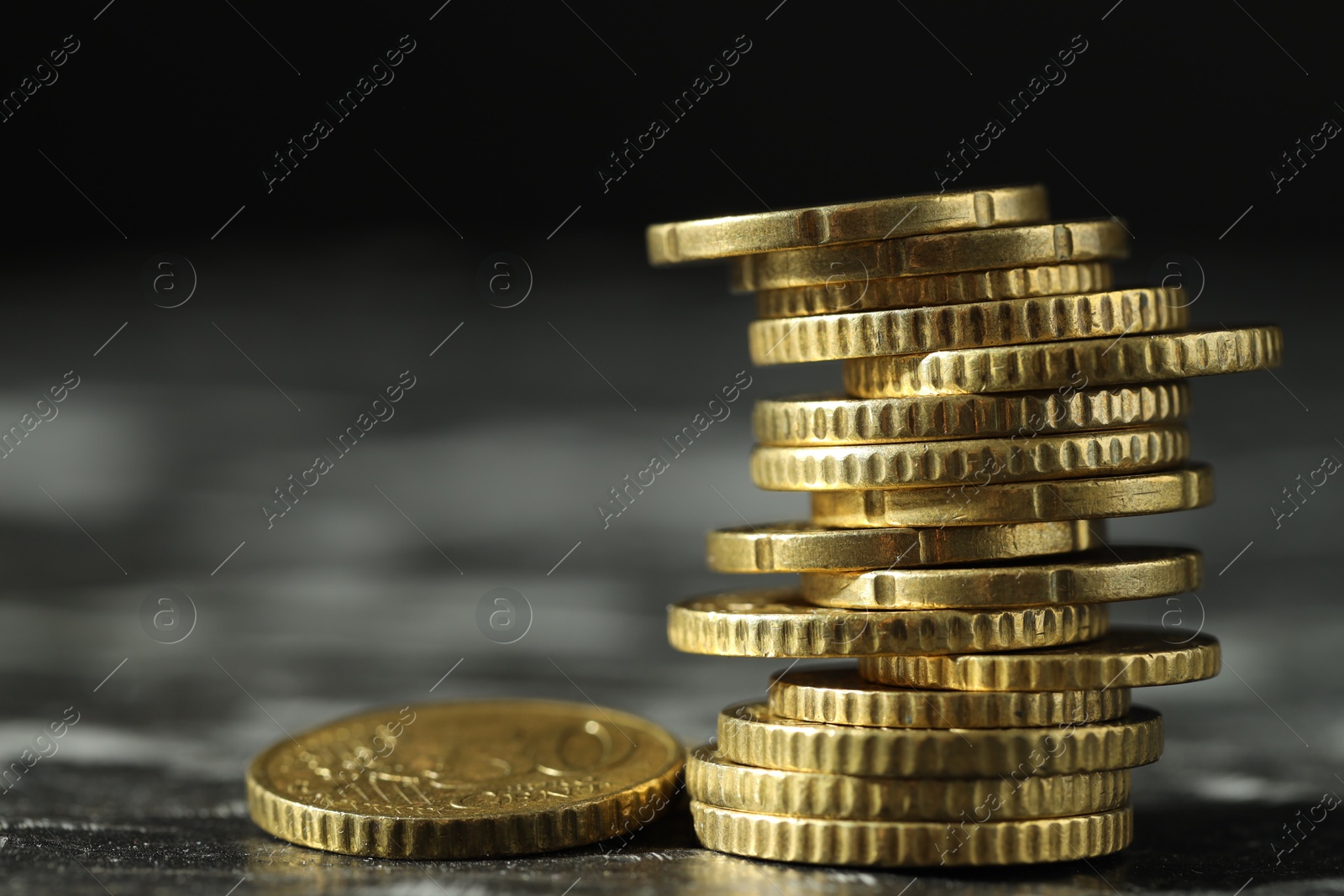 Photo of Stacked euro coins on dark table, closeup. Space for text