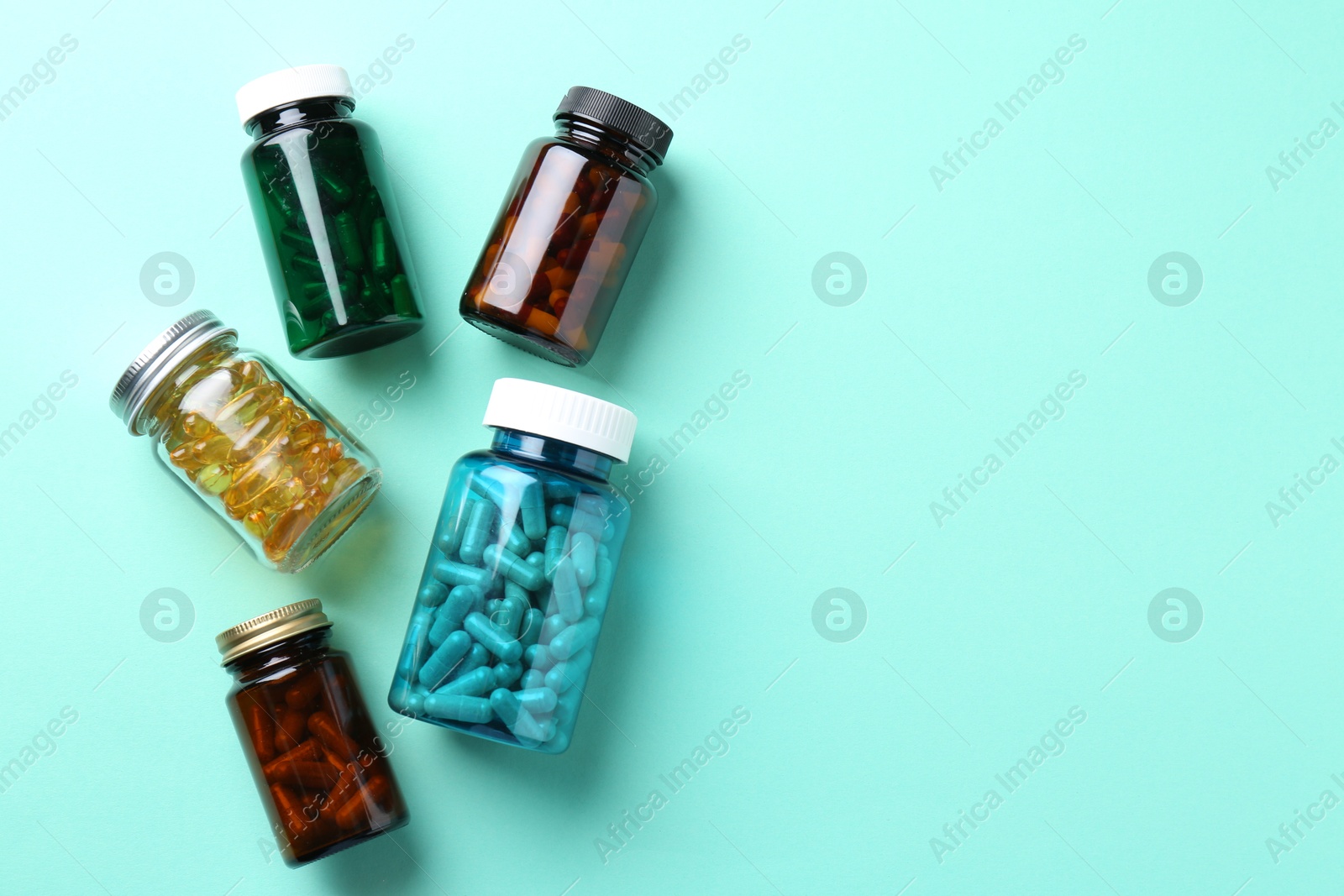 Photo of Pharmacist. Different pills in plastic bottles on light blue background, flat lay. Space for text