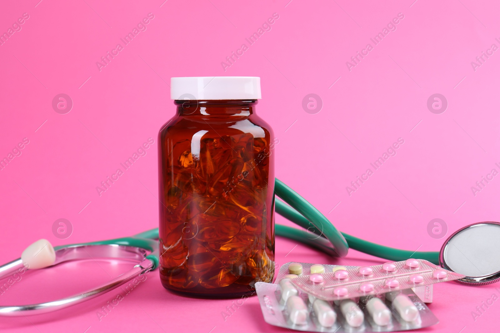 Photo of Pharmacist. Different pills and stethoscope on pink background