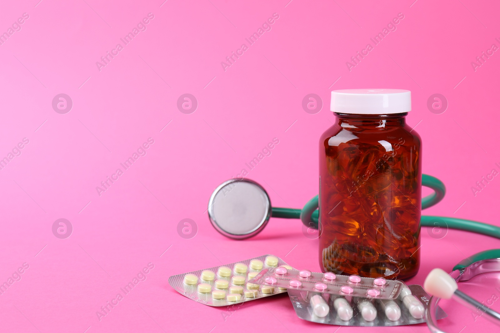 Photo of Pharmacist. Different pills and stethoscope on pink background, space for text