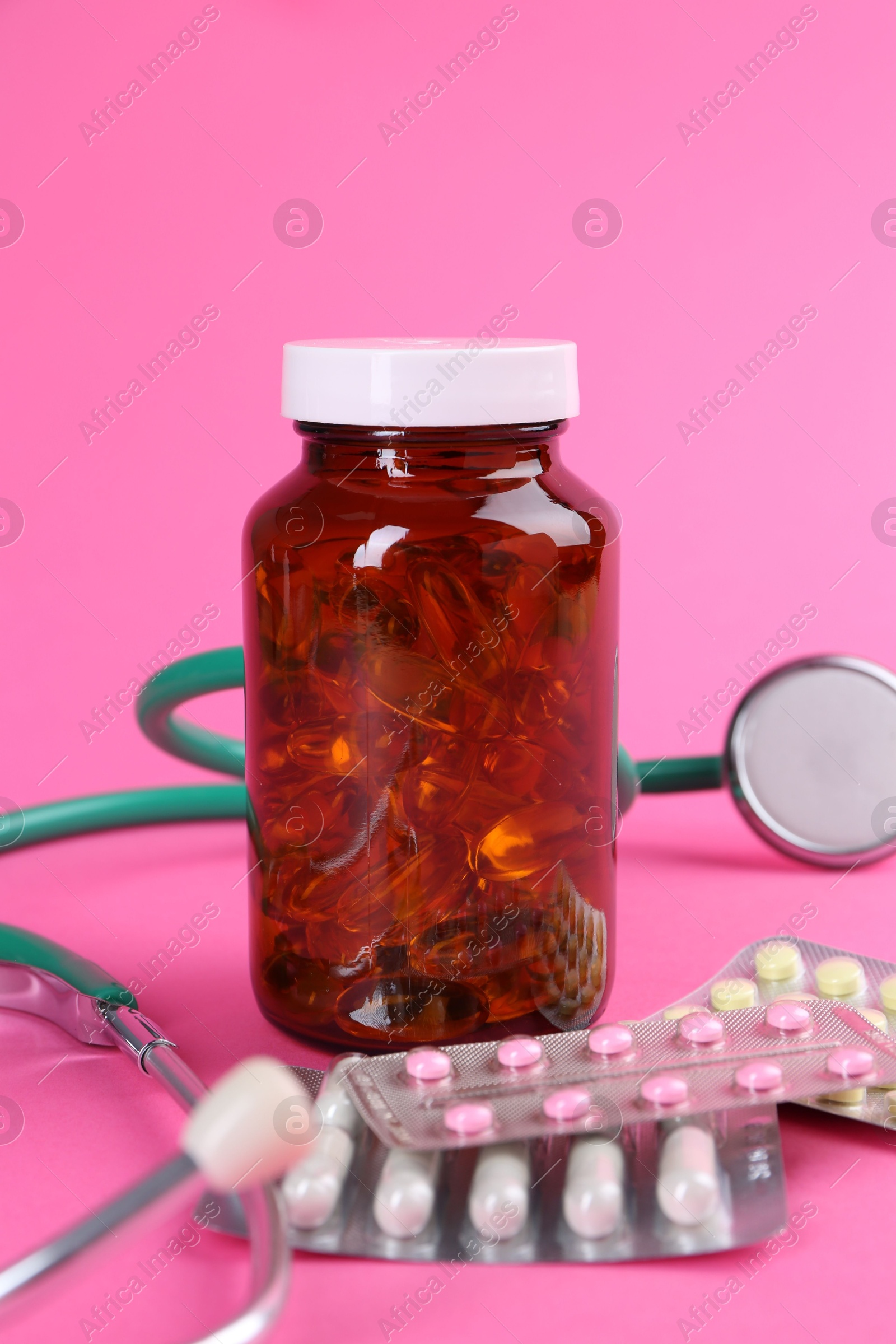 Photo of Pharmacist. Different pills and stethoscope on pink background