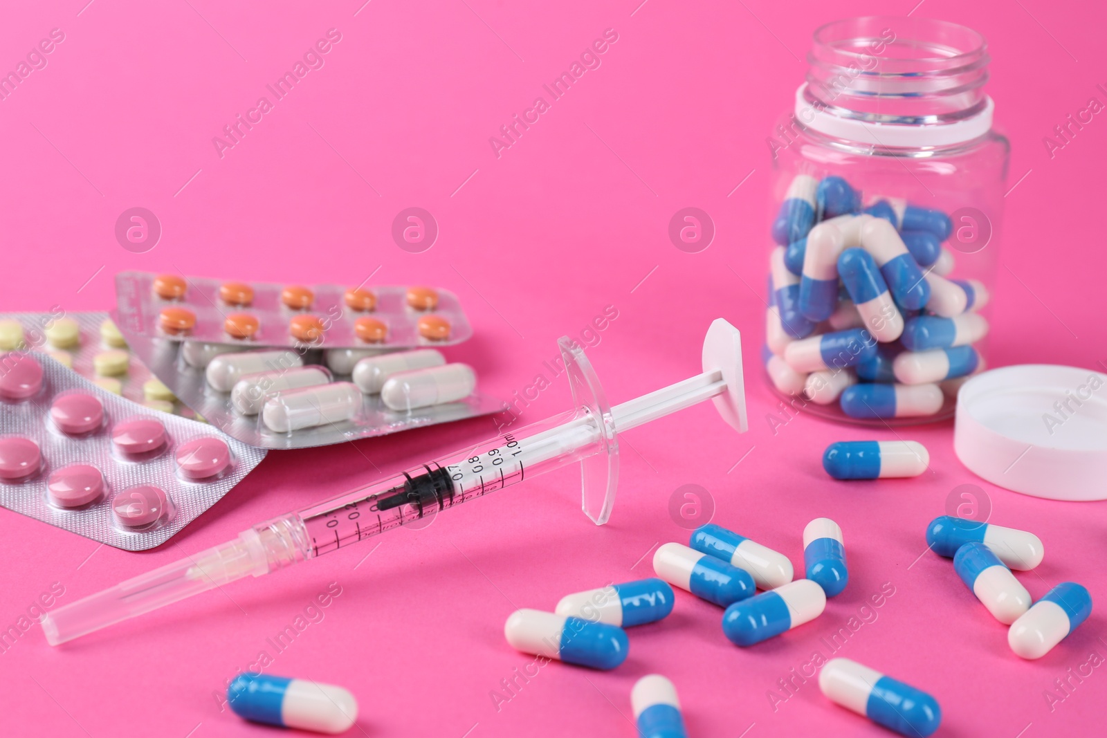 Photo of Pharmacist. Many different pills and syringe on pink background